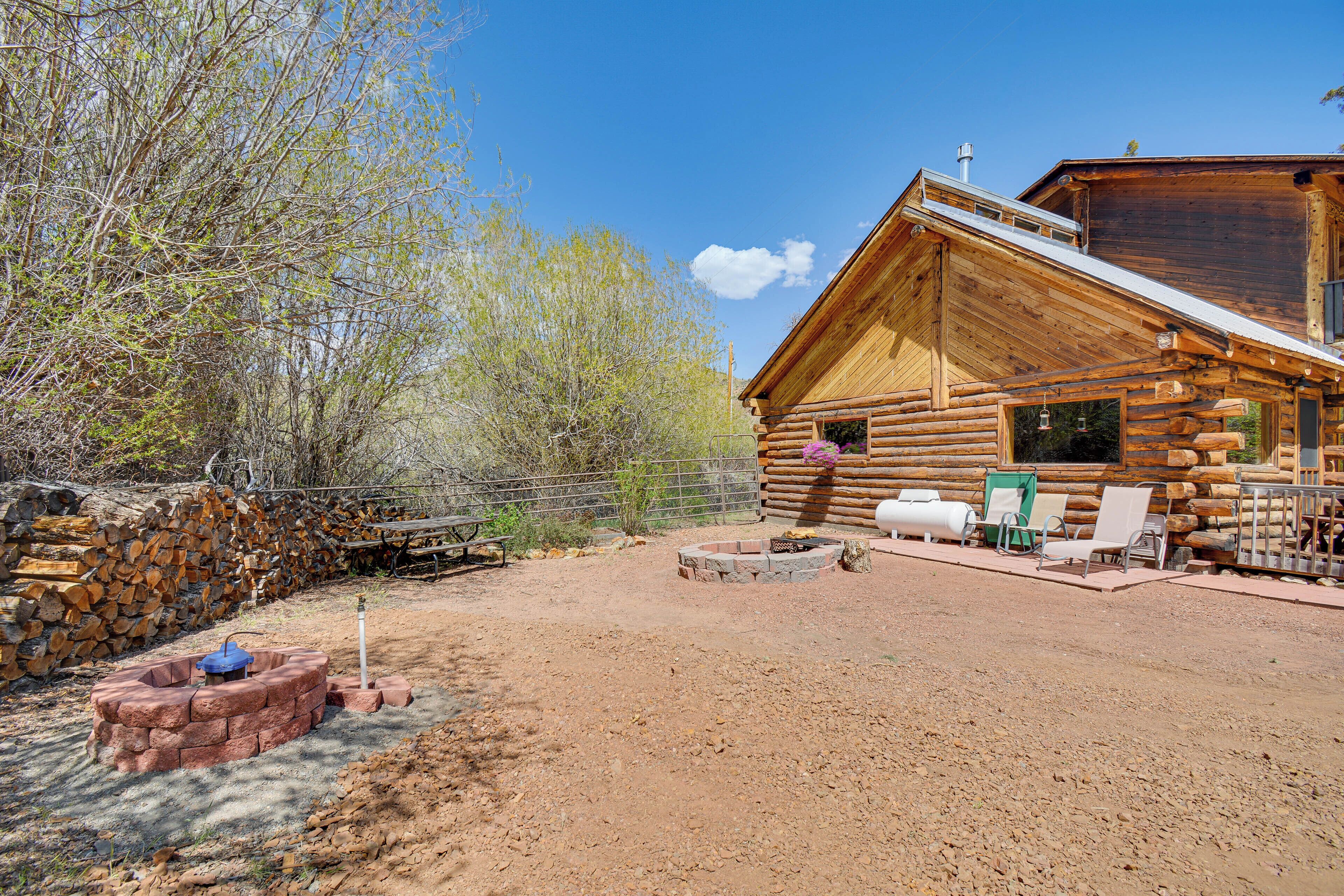 A log cabin with a fire pit, outdoor seating, and a stone wall.