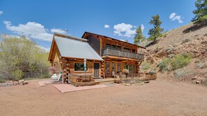 A log cabin with a balcony, a patio area, and a view of the surrounding landscape. - Fire Pit: 20-acre Creekfront Retreat in Gunnison! (Gunnison)