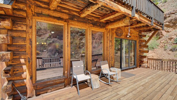 A wooden cabin with a deck, large windows, and outdoor seating. - Fire Pit: 20-acre Creekfront Retreat in Gunnison! (Gunnison)