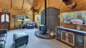 A log cabin interior with a fireplace, leather furniture, and mounted deer heads. - Fire Pit: 20-acre Creekfront Retreat in Gunnison! (Gunnison)