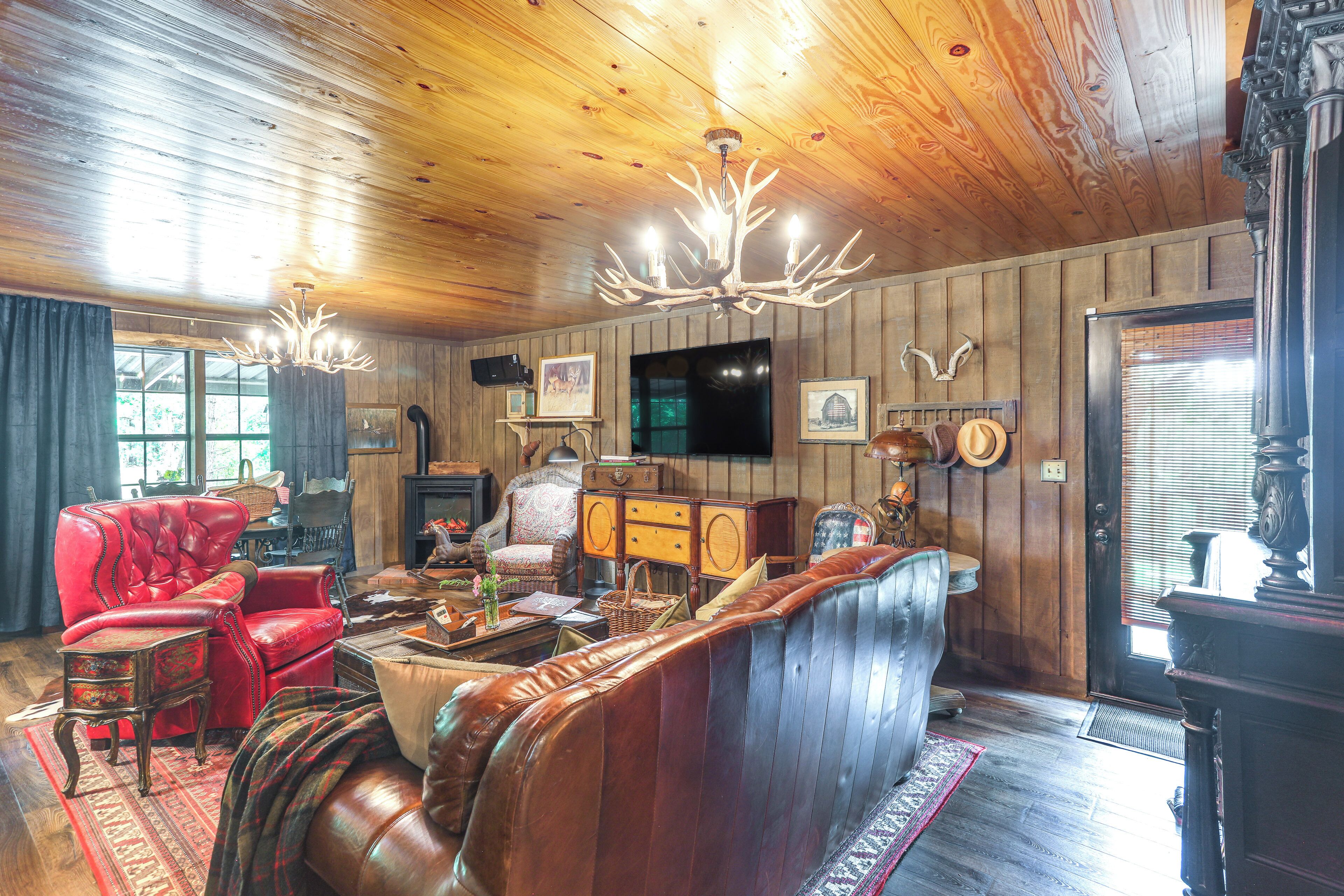 A rustic interior with a leather sofa, wooden walls, and a chandelier.