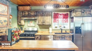 A kitchen with wooden cabinets, a stainless steel refrigerator, a stove, and a wooden countertop.