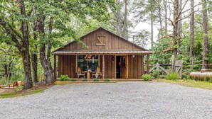 A rustic wooden cabin with a porch, surrounded by trees.