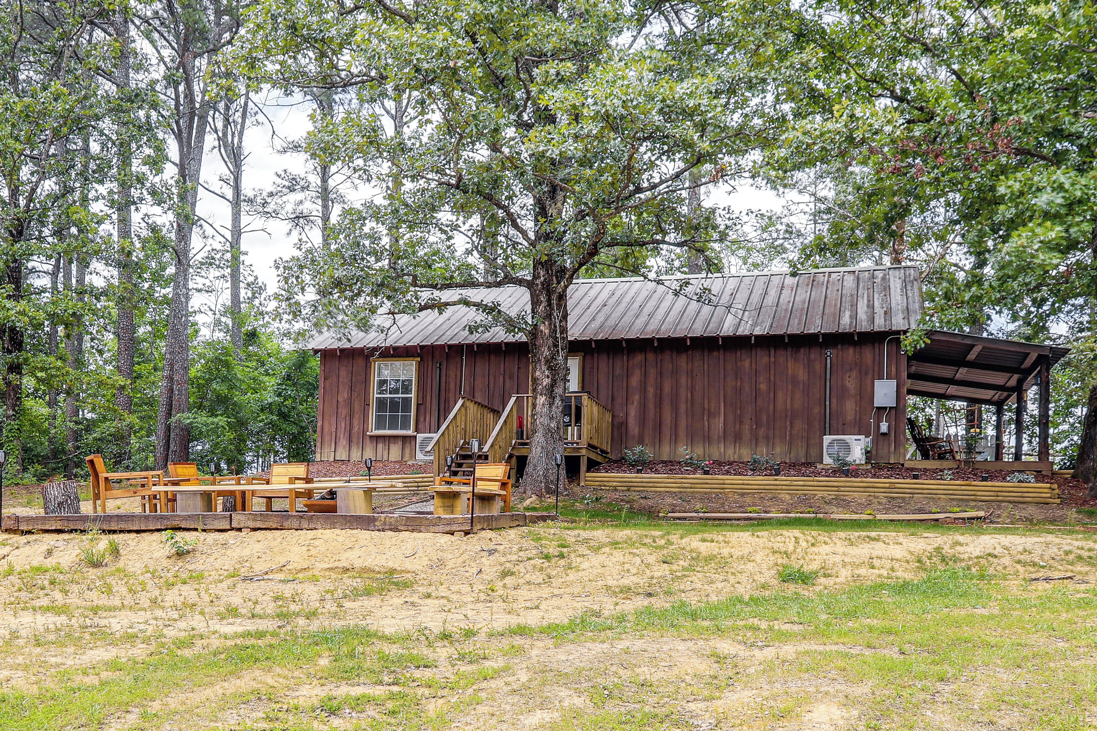 A rustic wooden cabin with a porch, surrounded by trees.