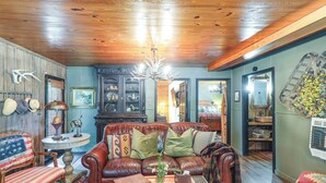 A cozy living room with a leather sofa, a coffee table with a vase, and a chandelier.