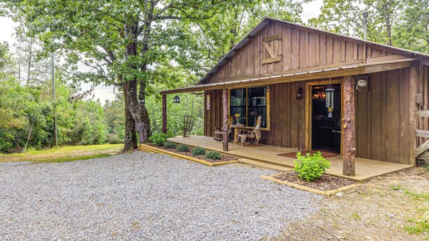 A wooden cabin with a porch, a dining area, and a visible entrance.