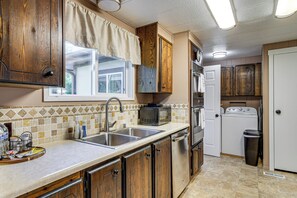 A kitchen with wooden cabinets, a stainless steel sink, a microwave, a dishwasher, and a washing machine. - Private Dock & Furnished Deck! Cozy Belfair Escape (Belfair)