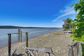 A pebbled beach with wooden structures, a clear sky, and distant hills. - Private Dock & Furnished Deck! Cozy Belfair Escape (Belfair)