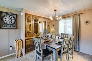 A dining room with a wooden table set for four, a dartboard, and a chandelier. - Trails End Retreat in Belfair w/ Private Dock (Belfair)
