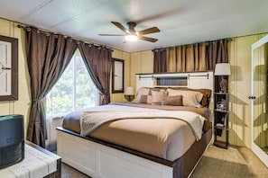 A bedroom with a bed, ceiling fan, window with curtains, bedside lamp, and a heater. - Private Dock & Furnished Deck! Cozy Belfair Escape (Belfair)