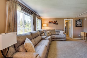 Una sala de estar moderna con un sofá modular, una lámpara, un dardo y vistas amplias a través de grandes ventanas.