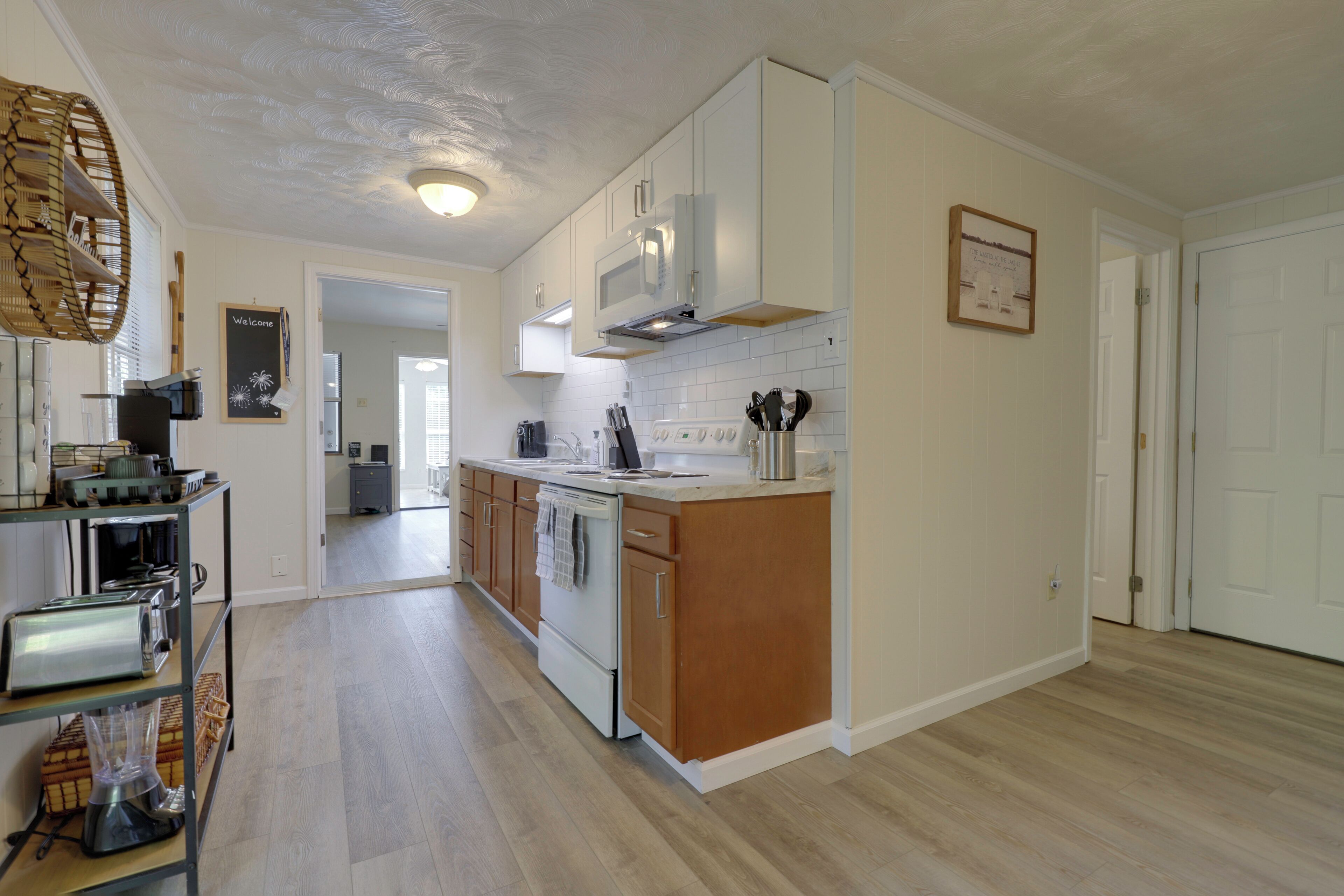 A modern kitchen with white cabinets, a stainless steel range hood, and a wooden island.