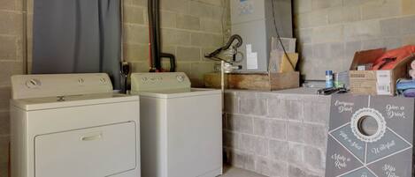 A laundry room with two washers and dryers, a water heater, and a dartboard with safety instructions.