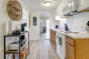 A kitchen with white cabinets, a microwave, a stove, and a coffee maker. There is a wooden shelf with kitchen utensils and a wicker basket. - Douglas Lake Gem on Private Cove w/ Amazing Views! (Dandridge)