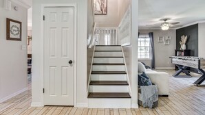 Eine Treppe führt zu einem Erkerbereich mit Deckenventilator, einem Kicker und einer Couch mit Zierkissen.