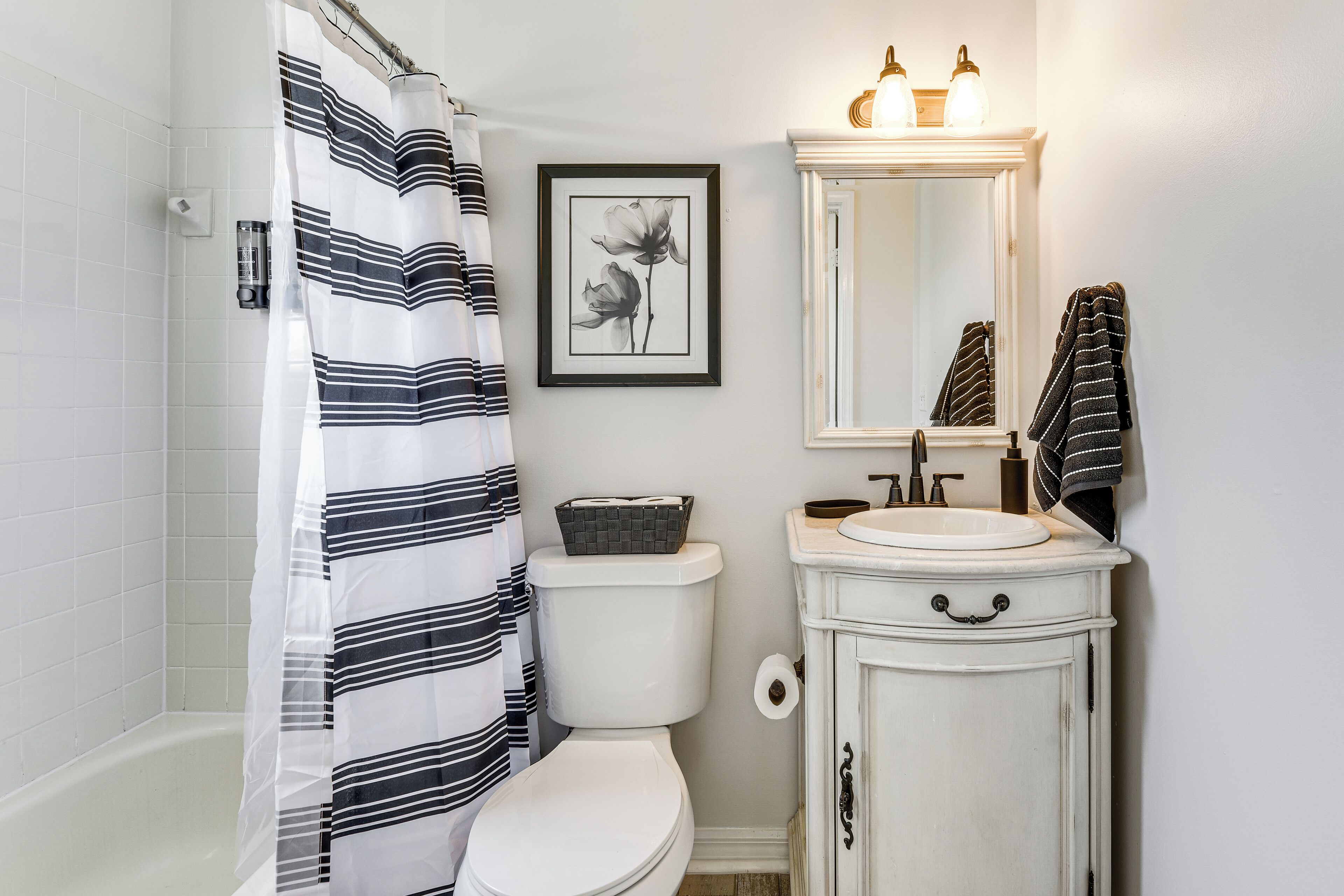 A bathroom with a white toilet, a white sink with a mirror above it, and a shower curtain.