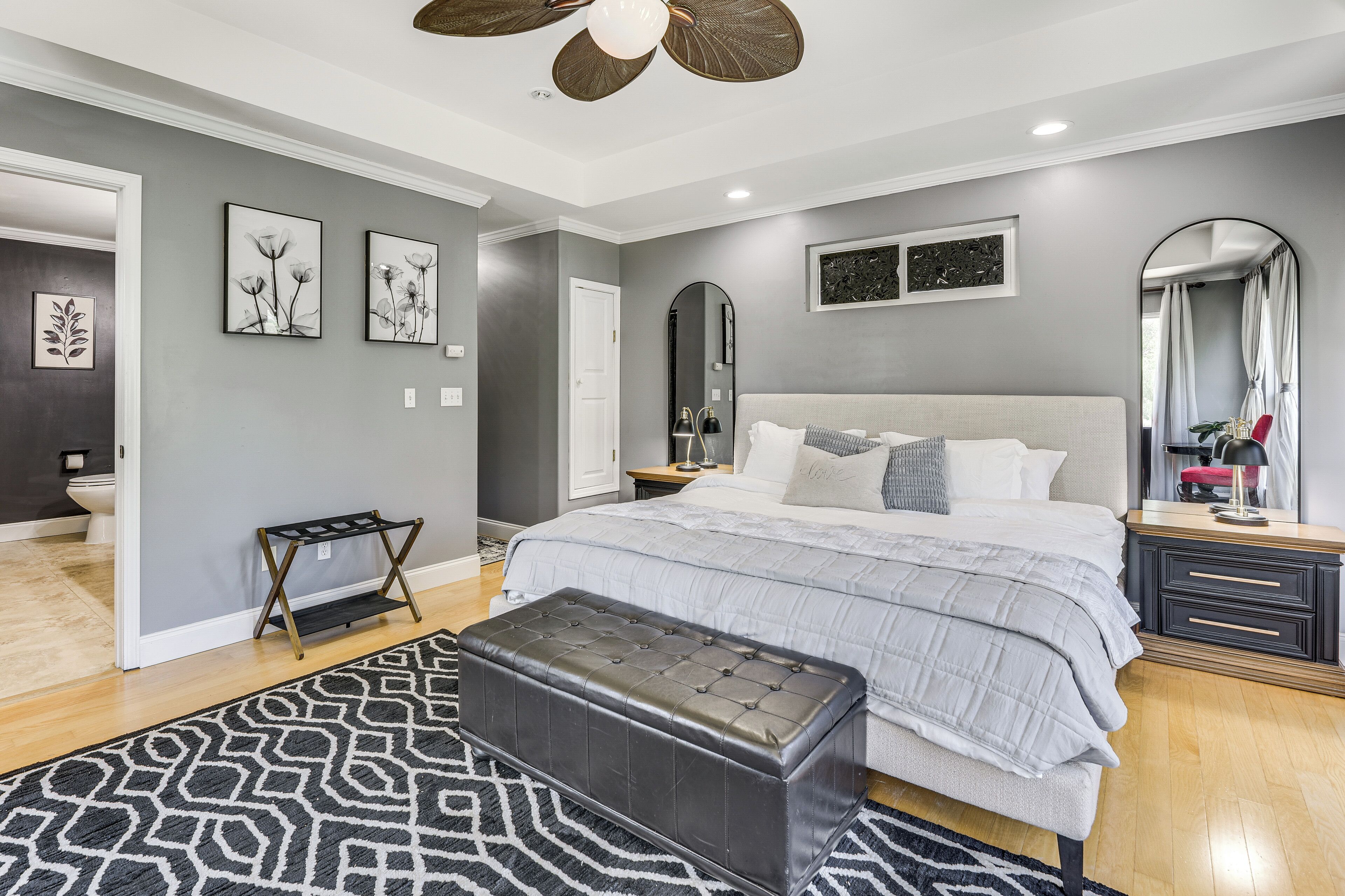 A bedroom with a bed, a bedside table, a mirror, and a wall-mounted artwork.