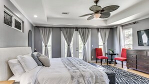 Ein Schlafzimmer mit einem Bett, einem Deckenventilator, einem Schminktisch und einem Fenster mit Vorhängen.