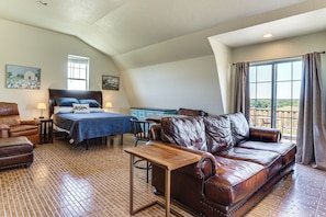 Ein Schlafzimmer mit einem Bett, einem Ledersofa, einem Holztisch und einem Schreibtisch.
