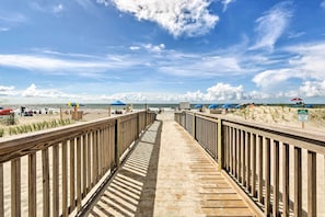 A wooden boardwalk leading to a beach with umbrellas and a sign indicating dune rebuilding. - Tides, Tennis & Tan Lines: Hilton Head Condo! (Hilton Head Island)