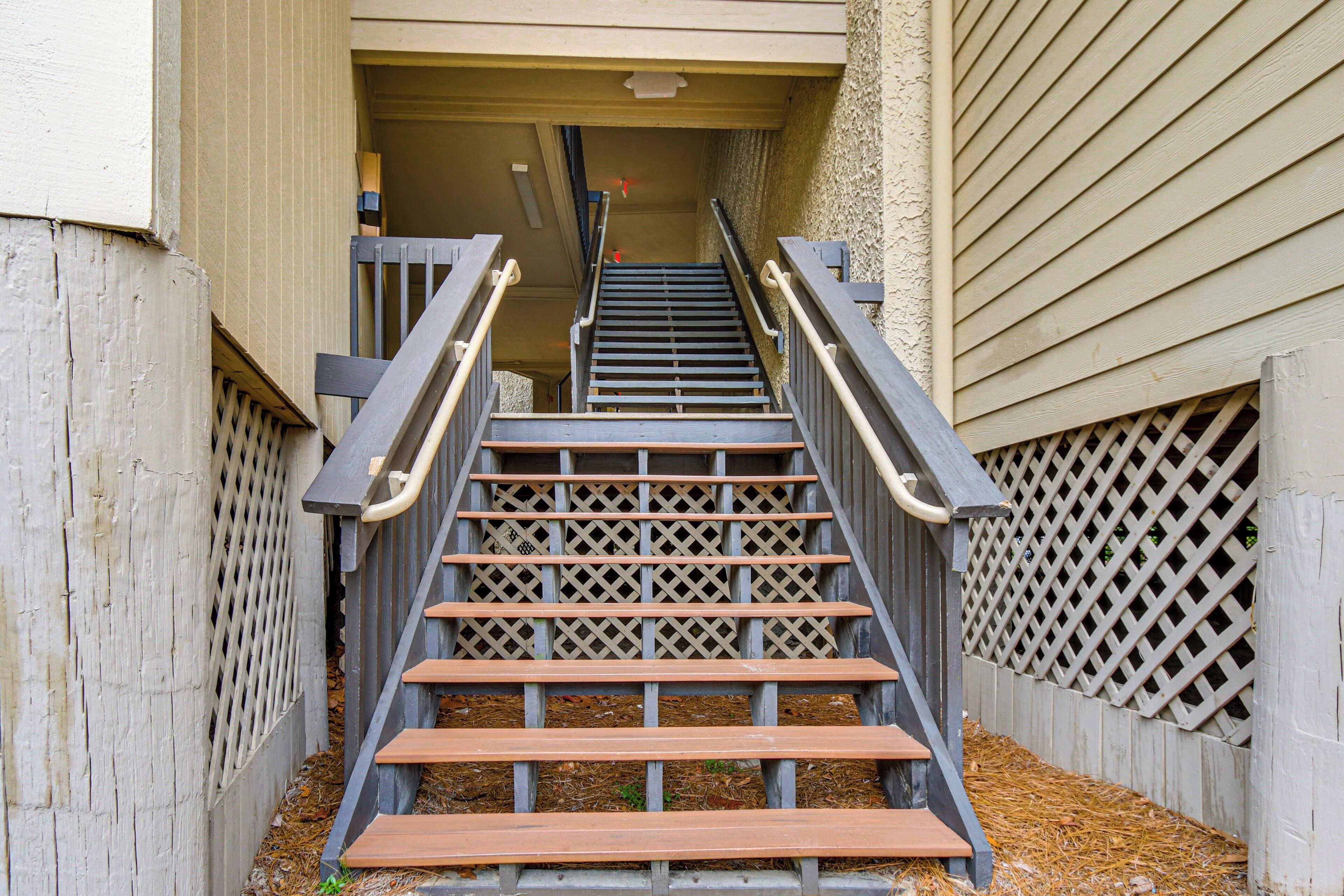 A set of wooden stairs with metal railings leading to a building entrance.