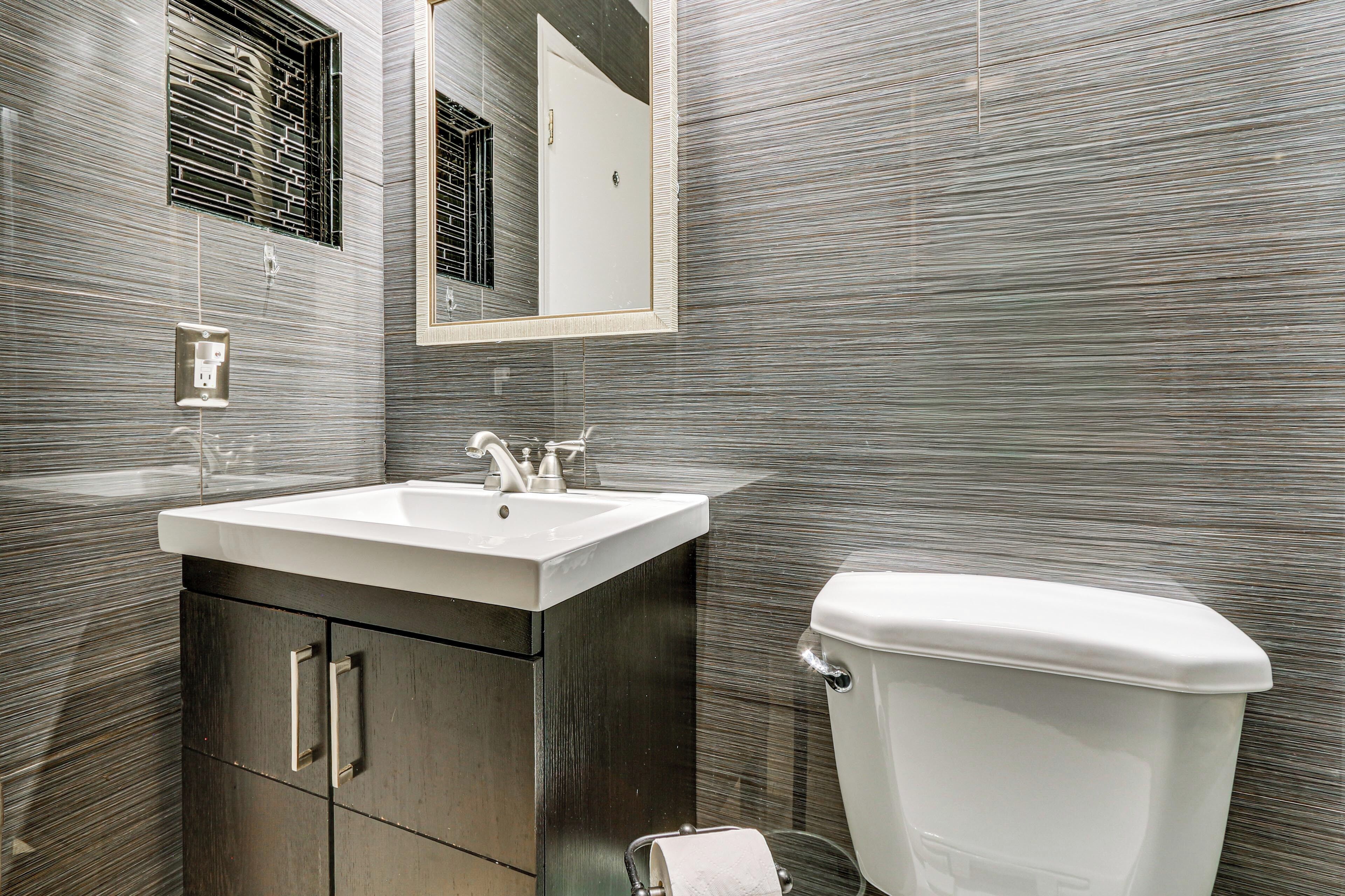 A modern bathroom with a sink, mirror, and toilet.