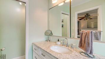 A bathroom with a marble sink, a mirror, a towel rack, and a ceiling fan.