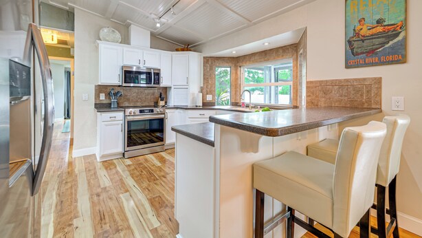 Una cocina moderna con armarios blancos, electrodomésticos de acero inoxidable y una isla grande con taburetes de bar.