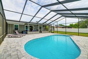 Ein Swimmingpool mit überdachter Terrasse, Liegestühlen und Blick auf die umliegende Landschaft.