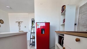 A kitchen with a red refrigerator, white cabinets, and a tiled floor. - Departamento 1501 Movistar Arena (Santiago)