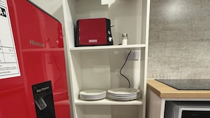 A kitchen with a red appliance, white shelves, and a microwave. - Departamento 1501 Movistar Arena (Santiago)