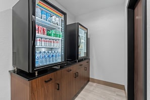 Deux distributeurs de boissons proposant une variété de breuvages, un meuble en bois et un sol carrelé.