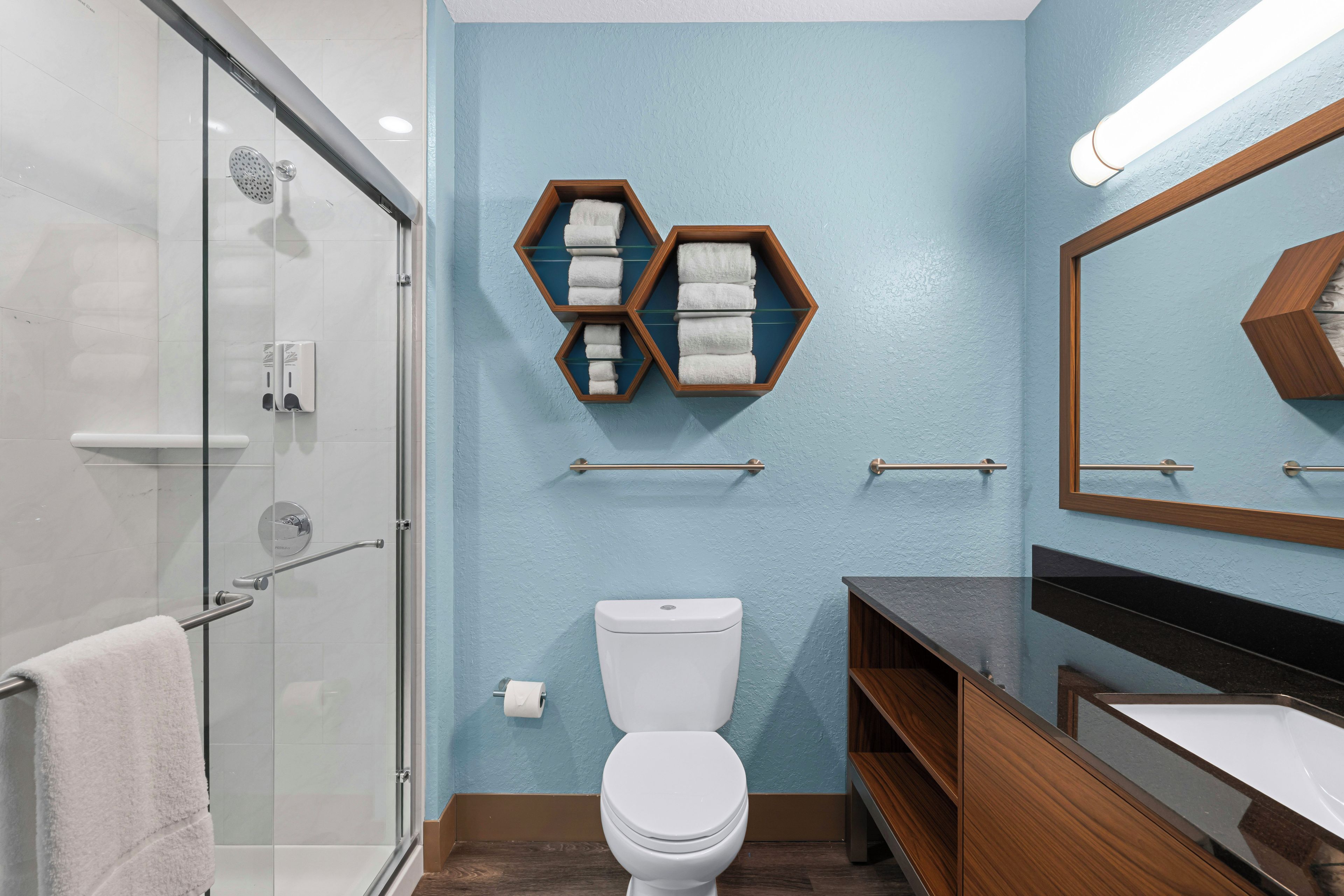 Un baño moderno con cabina de ducha de vidrio, inodoro y tocador con espejo.
