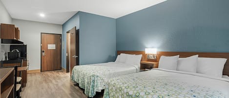 Una habitación de hotel con dos camas, una kitchenette y un escritorio de madera.