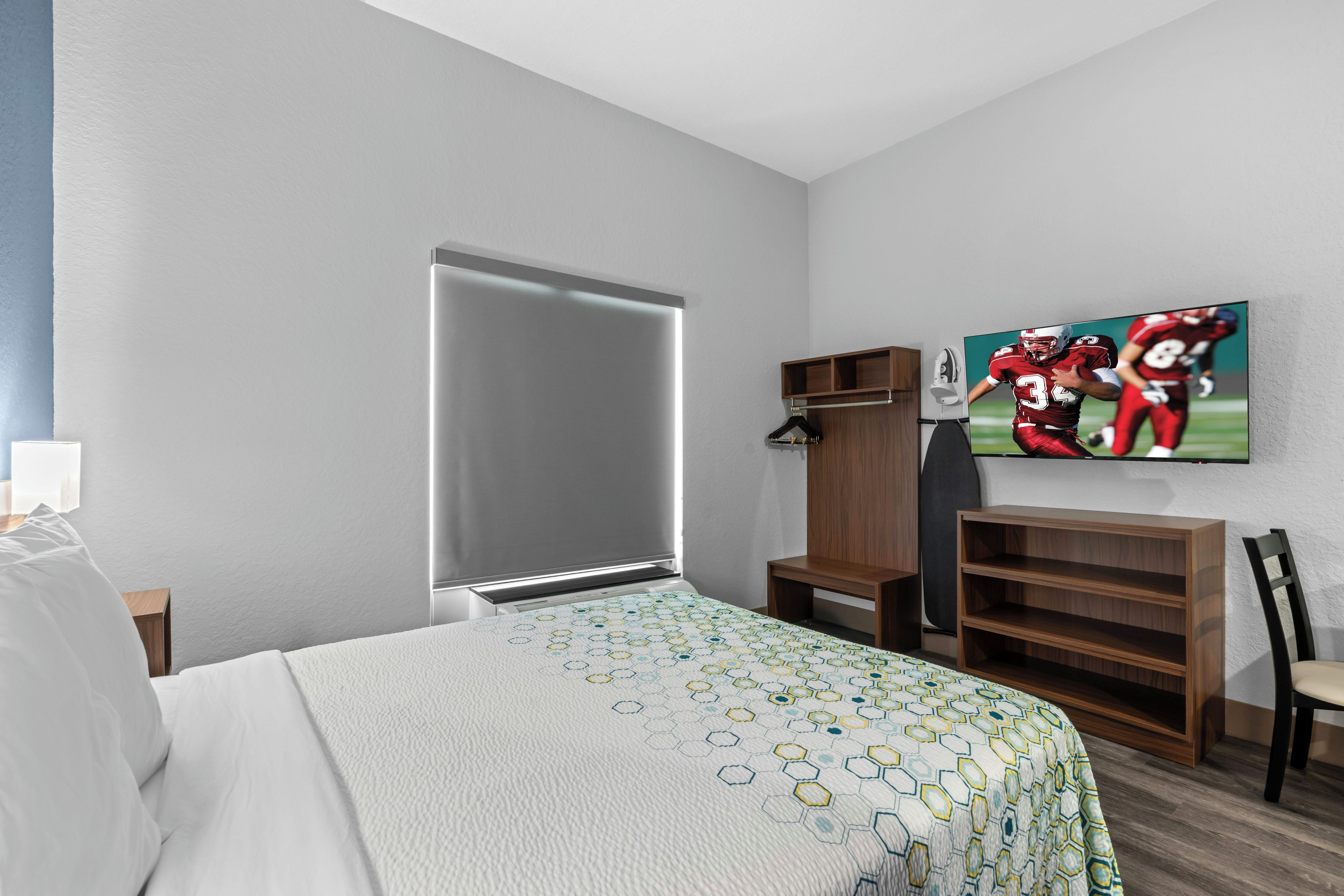A hotel room with a bed, a wardrobe, a TV, and a shelf.