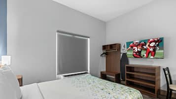 A hotel room with a bed, a wardrobe, a TV, and a shelf.
