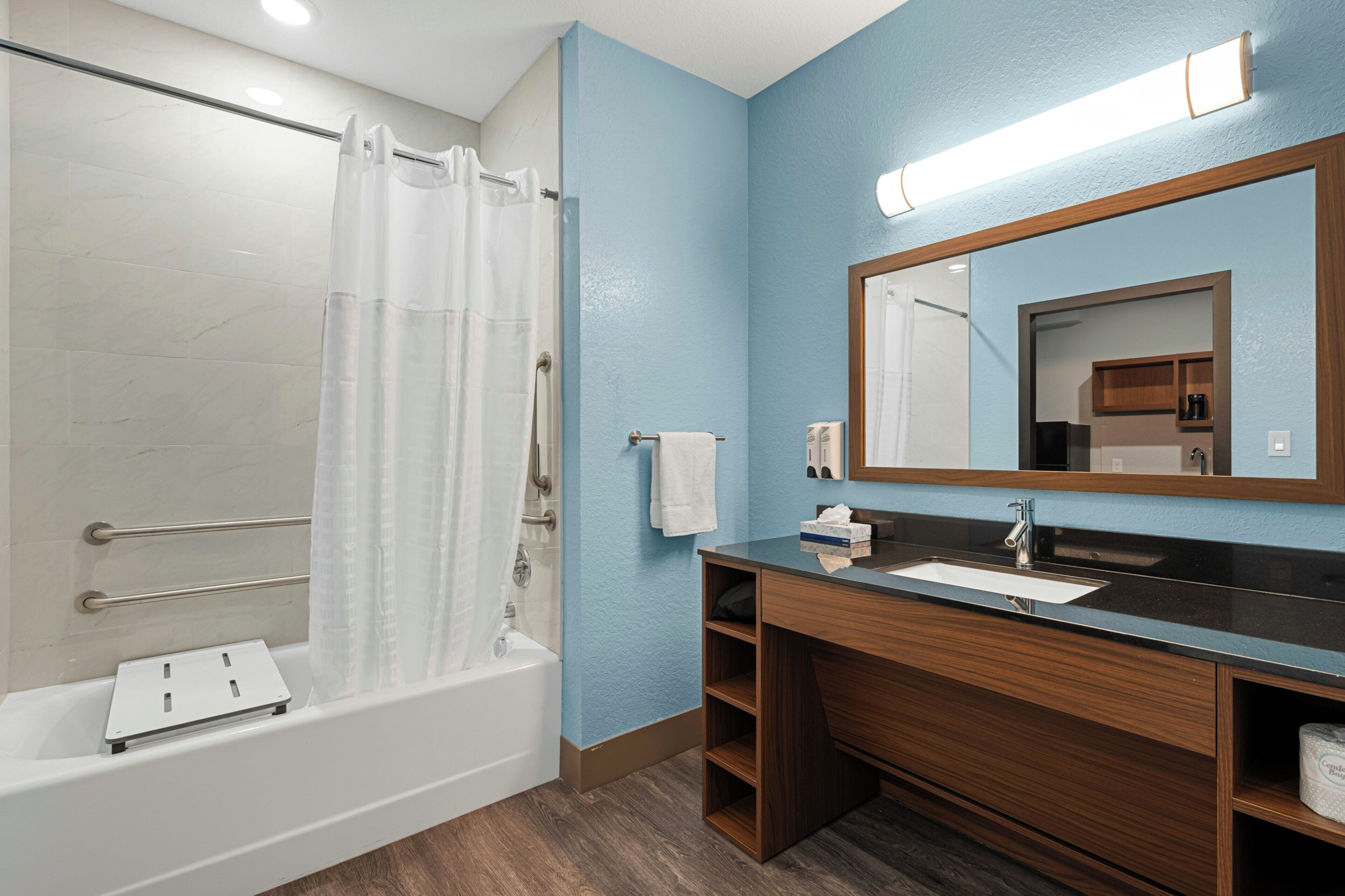 Un baño con bañera, lavabo, espejo y cortina de ducha.