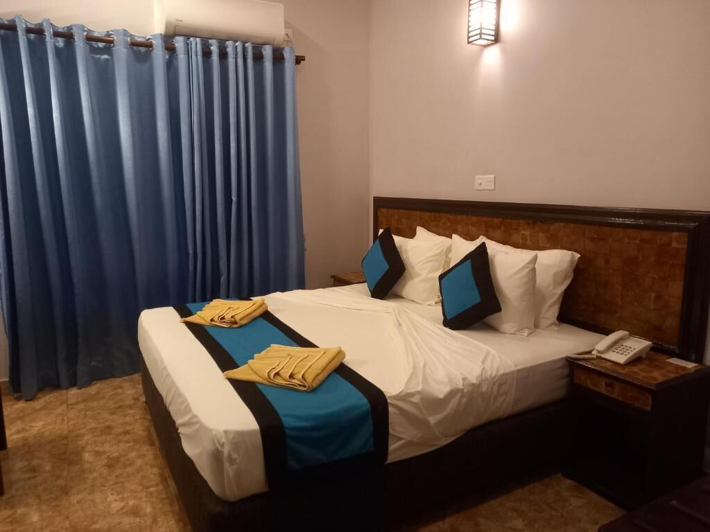 Una habitación de hotel con una cama, una mesita de noche, un teléfono y una cortina.