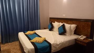 Una habitación de hotel con una cama, una mesita de noche, un teléfono y una cortina.