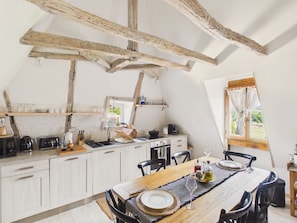A rustic kitchen with exposed beams, a dining table set for two, and a window with a view. - Authentic family home near village - 6 ppl (Domme)