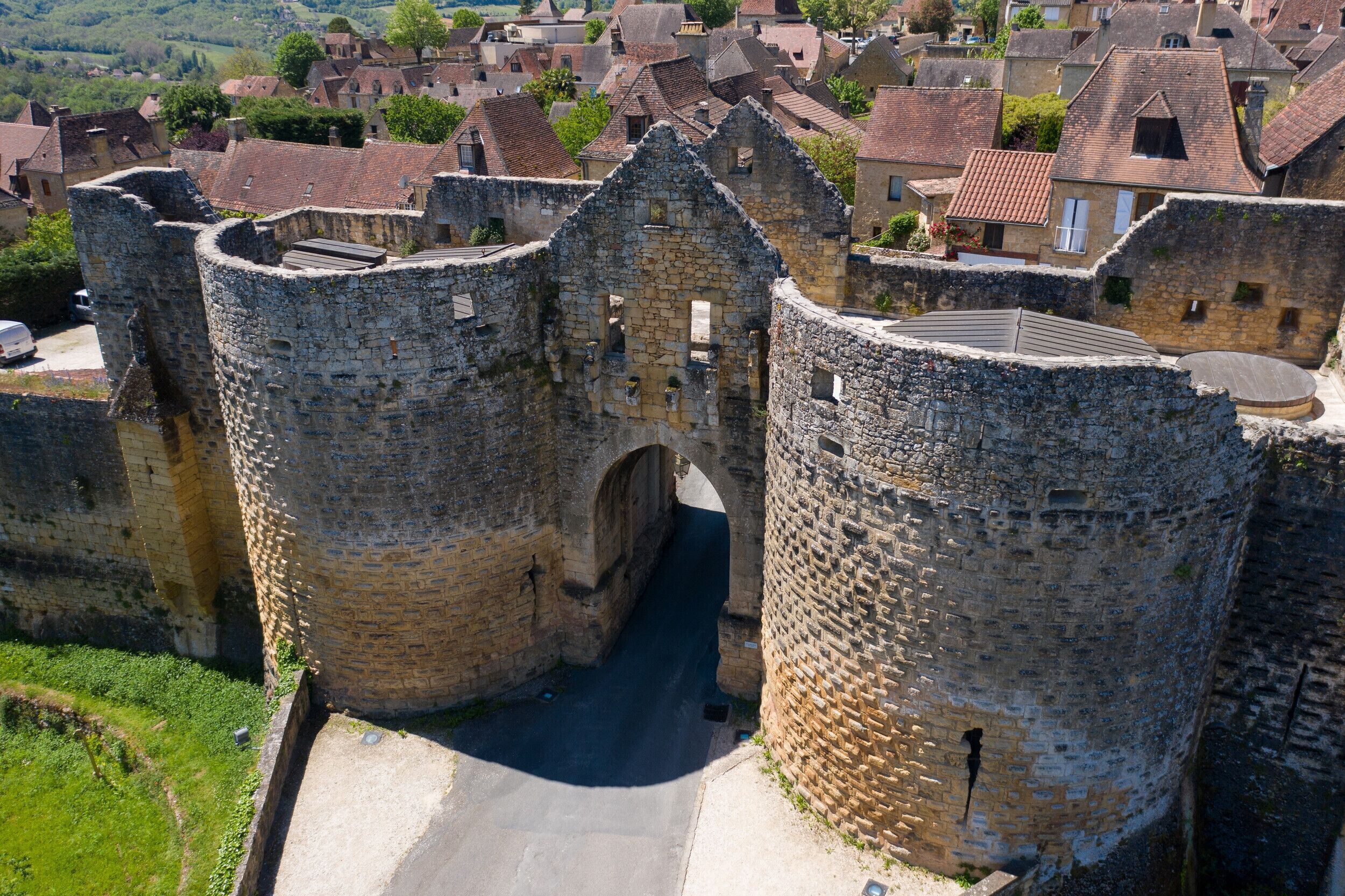 A medieval stone castle with a central archway, surrounded by residential buildings.