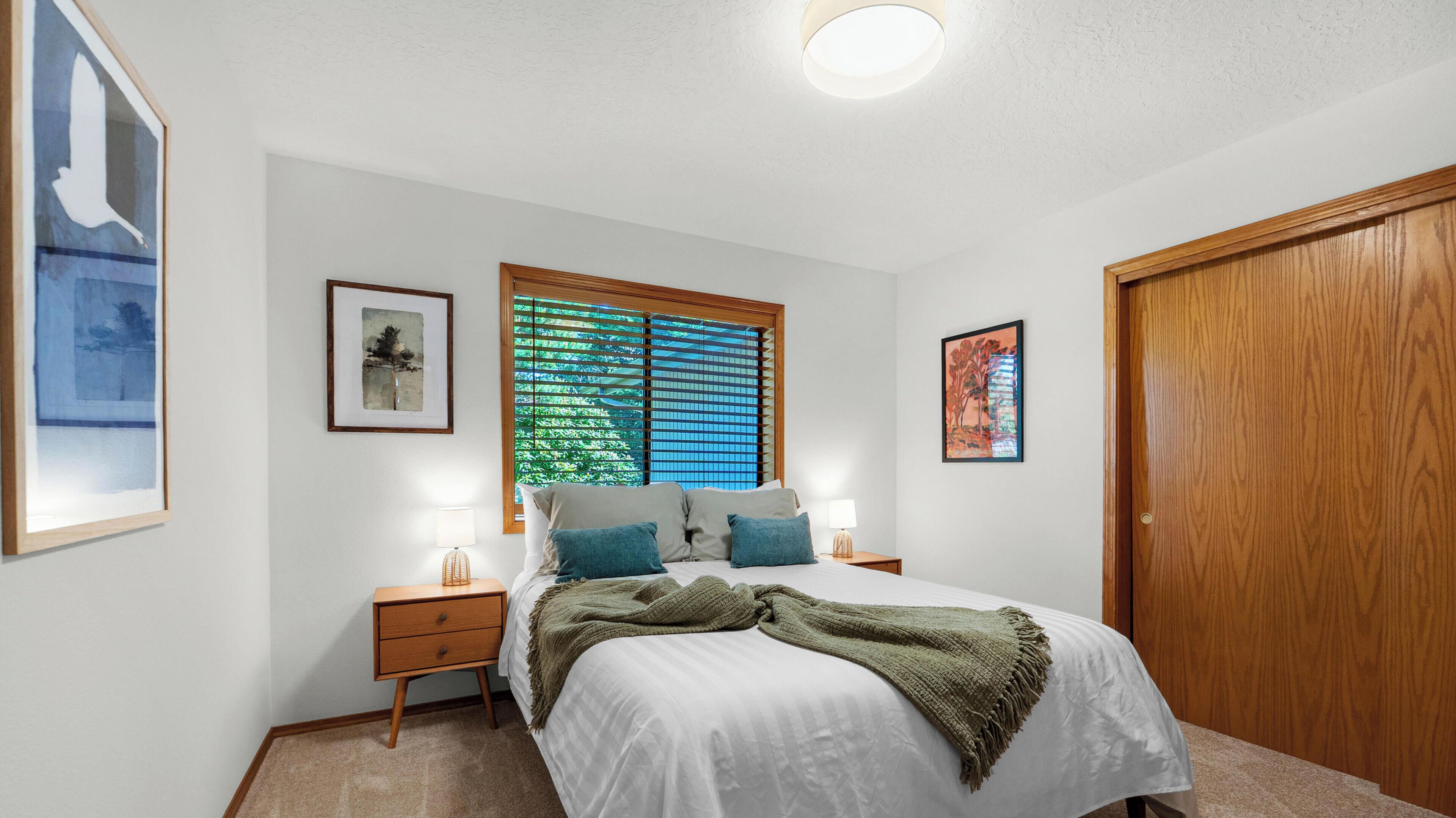 Una camera da letto con un letto, due comodini, una finestra con tende e una porta in legno.