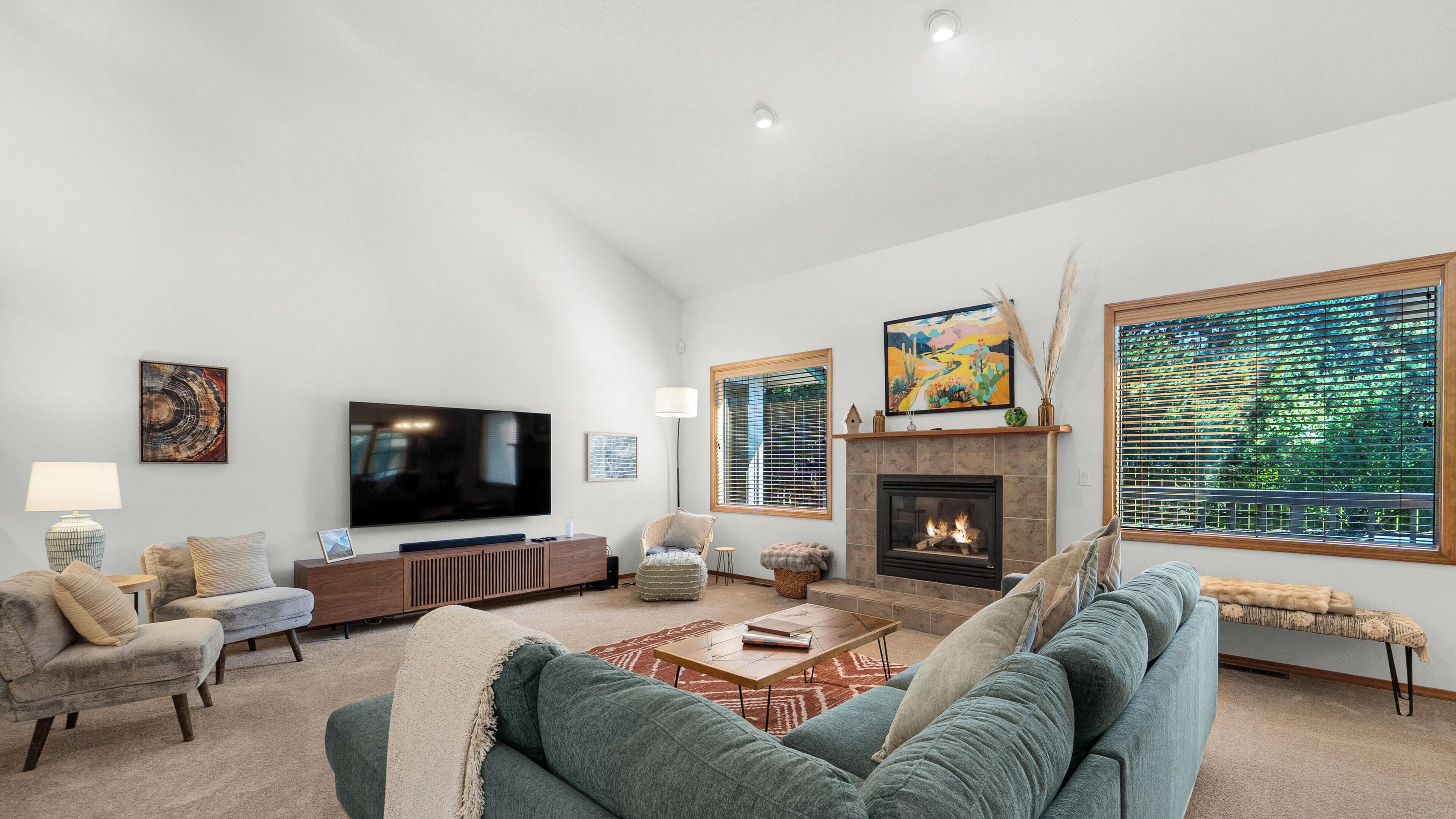 A living room with a flat-screen TV, fireplace, and large windows.
