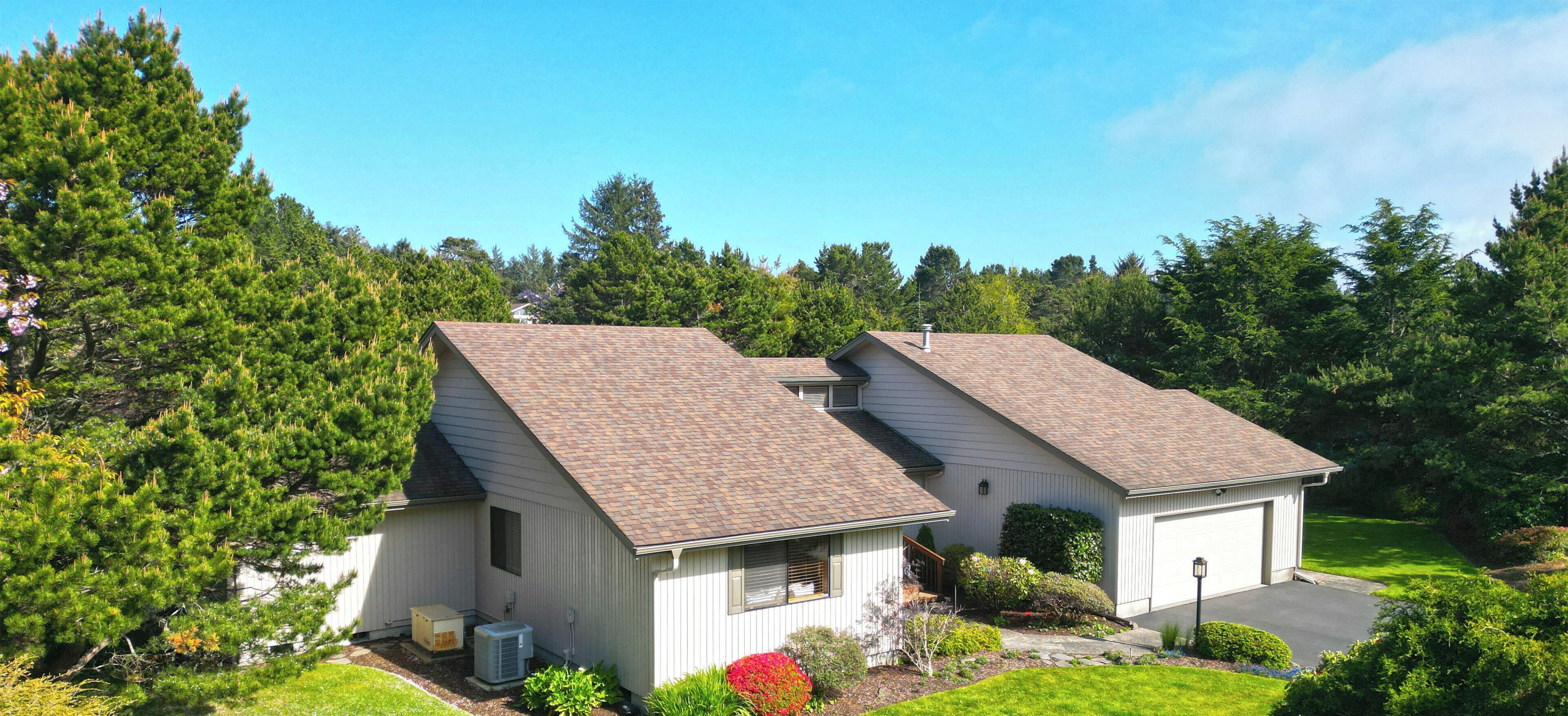 Single-level vacation home nestled among mature evergreens and lush gardens, offering a peaceful retreat with private parking and spacious grounds surrounded by natural beauty.