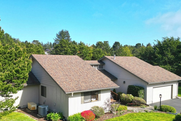 Single-level vacation home nestled among mature evergreens and lush gardens, offering a peaceful retreat with private parking and spacious grounds surrounded by natural beauty.
