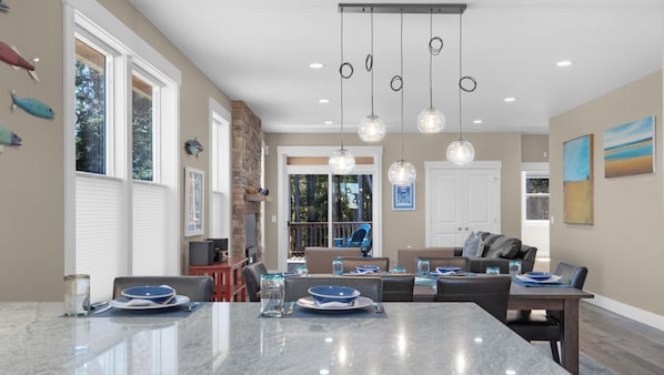 A spacious kitchen with a large island, dining area, and a view of the outdoors. - Mac's Surf Shack at Seaside Beach (Seaside)