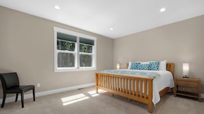 A bedroom with a wooden bed, a nightstand, a chair, and a window with blinds. - Mac's Surf Shack at Seaside Beach (Seaside)