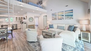 A spacious living area with a staircase, a dining area, and a kitchen. - Sea Colony Coastal Escape: Steps from Trolley stop, pools, tennis, fitness center and more!  Private Beach! (Bethany Beach)