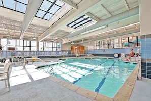 Ein Hallenbad mit klarem Wasser, einem Sprungbrett und einem Rettungsschwimmerstuhl.