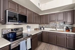 A modern kitchen with dark brown cabinets, stainless steel appliances, and a stone backsplash. - Luxury Cave Creek Townhome Near Golf, TPC & Scottsdale (Phoenix)